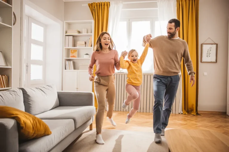 A mother and father lifting their daughter as she jumps in the air.
