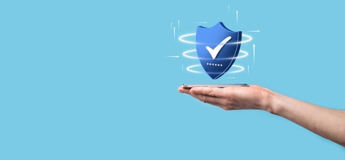An outstretched hand holding a blue shield with a checkmark.